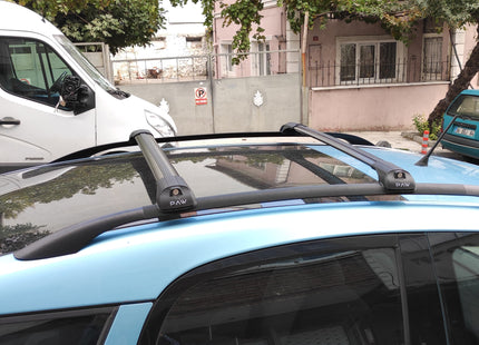 Car with roof rack on a street with buildings and trees in the background